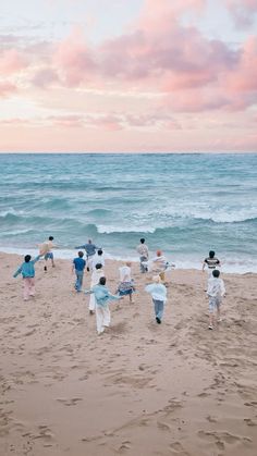 several people on the beach playing with a frisbee in the sand near the water