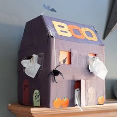 a halloween house made out of cardboard sitting on top of a mantle