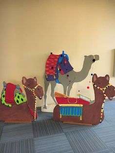 three cardboard camels are sitting next to each other on the floor in front of a wall