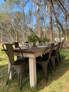 a wooden table with chairs around it in the grass