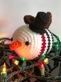 a knitted bird with a hat on top of it's head and lights around its neck