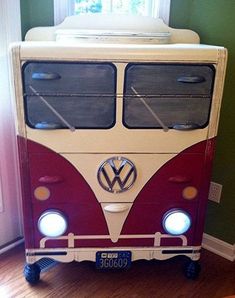 a red and white toy bus sitting on top of a hard wood floor next to a window