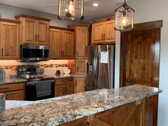 a kitchen with granite counter tops and wooden cabinets, an island in the foreground