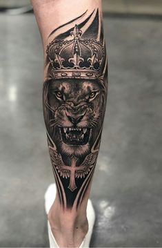 a man's leg with a lion wearing a crown and cross tattoo on it