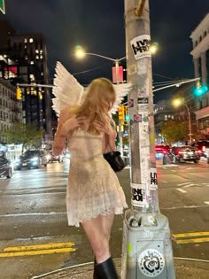 a woman dressed as an angel is standing next to a pole with stickers on it