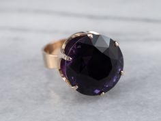 This ring is truly gorgeous! A large and beautiful medium purple amethyst sits in the center, with an amazing cut and vibrant purple color that flickers with bright pops of violet! The stone is expertly cut to really display the stone’s color and sparkle! The classic mid-century mounting is all this stone needs to frame it to perfection! Metal: 14K Yellow Gold Gem: Amethyst 19.81 Carats Gem Measurements: 17.6 mm, Round Ring Size: 7 Marks: "585 FINLAND" Stamped on the inside band Purple Faceted Ring For Formal Occasions, Formal Faceted Purple Ring, Formal Purple Faceted Ring, Faceted Purple Amethyst Ring For Formal Occasions, Formal Faceted Purple Amethyst Ring, Formal Purple Amethyst Ring With Round Stone, Faceted Purple Amethyst Ring Fine Jewelry, Round Amethyst Ring With Diamond Cut, Yellow Gold Amethyst Ring