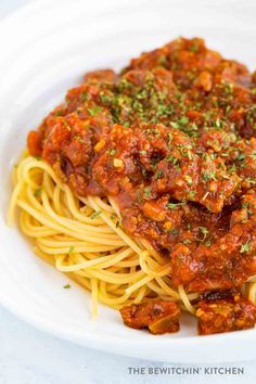 spaghetti with meat sauce and parsley on top in a white bowl, ready to be eaten