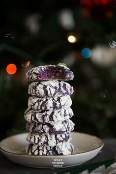 a stack of cookies sitting on top of a white plate next to a christmas tree