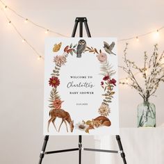 a welcome sign is on an easel next to a vase with flowers and birds