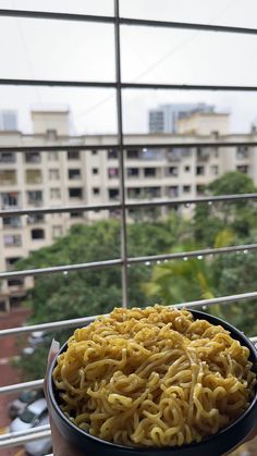 a person holding a bowl of noodles in front of a window