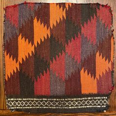 an orange and brown rug on top of a wooden table next to a wall mounted clock