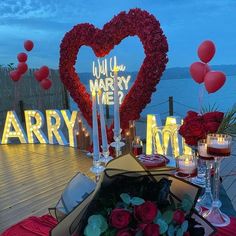 a table with flowers and candles on it in front of a sign that says marry me