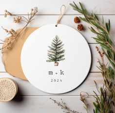 a christmas ornament with a pine tree on it next to some dried plants