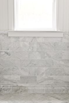 a bathroom with marble tile and a window in the backround, along with a white toilet