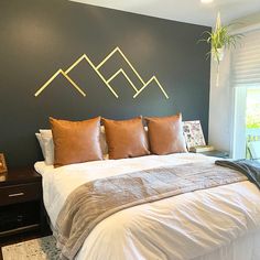 a large bed with pillows and blankets in a bedroom next to a wall mounted plant