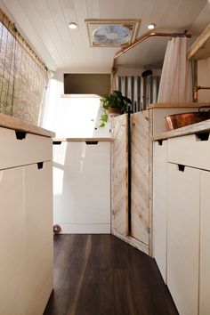 the inside of a tiny house with wood flooring and white cupboards on both sides