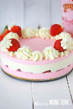 a pink cake with white frosting and strawberries on top, next to a cup of milk