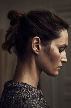 a woman with her hair in a messy topknott looks off to the side