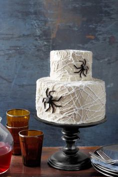 a three tiered cake decorated with spider webs and candles on a wooden table