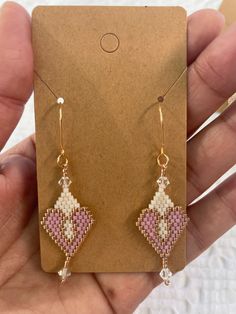 a pair of pink and white beaded earrings in front of a brown card holder