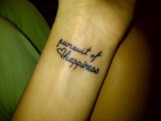 a small wrist tattoo with the words pursuit of happiness