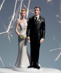 a bride and groom figurine standing on top of a cake with fireworks in the background