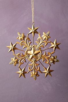 a gold snowflake ornament hanging on a purple wall