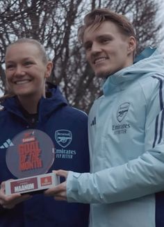 two people standing next to each other holding up a plaque that says goal of the month