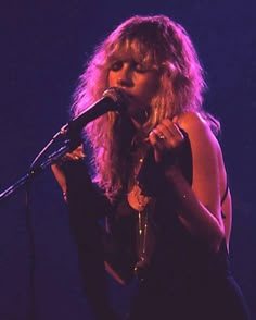 a woman standing in front of a microphone on stage