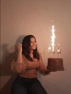 a woman holding a chocolate cake with sparklers on it