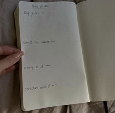 a hand holding an open notebook with writing on it