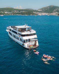 a large white boat floating on top of the ocean next to another boat with people in it