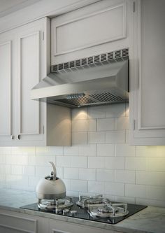 a stove top oven sitting inside of a kitchen next to white cupboards and drawers