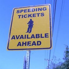 a yellow speed ticket sign sitting on the side of a road