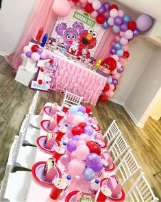 the table is set up for a sesame street birthday party with balloons and cupcakes