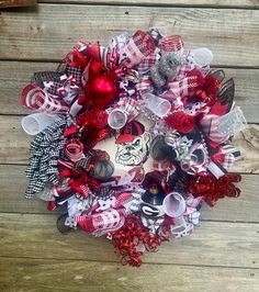 a wreath with red, white and silver ornaments on it sitting on a wooden surface