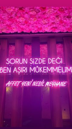 the neon sign is lit up in front of a building with pink flowers on it