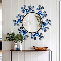 a mirror on the wall above a table with vases and plants in front of it