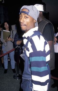 a man wearing a striped shirt and hat standing in front of a group of people