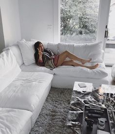 a woman laying on top of a white couch