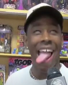 a man with his tongue hanging out in front of a book shelf holding a microphone