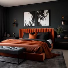 a bedroom with black walls, orange bedding and two pictures on the wall above it