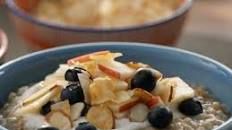 a bowl of oatmeal with blueberries, apples and bananas in it