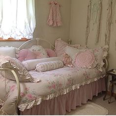 a pink and white bed in a bedroom next to a window