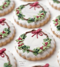 decorated cookies with bows and holly on them sitting on a white tablecloth covered in icing