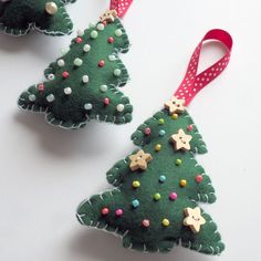 three felt christmas trees with bows on them