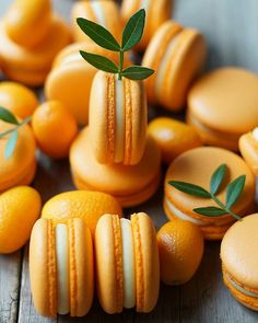 macaroons and oranges arranged on a wooden table with leaves sprouting out of them