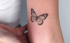 a woman's arm with a small butterfly tattoo on the left side of her arm