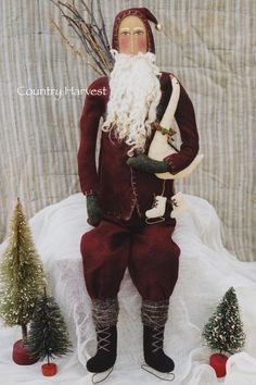 a statue of santa claus is posed next to some christmas trees and small evergreens