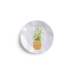 a white plate with a pineapple painted on the front and bottom, against a white background